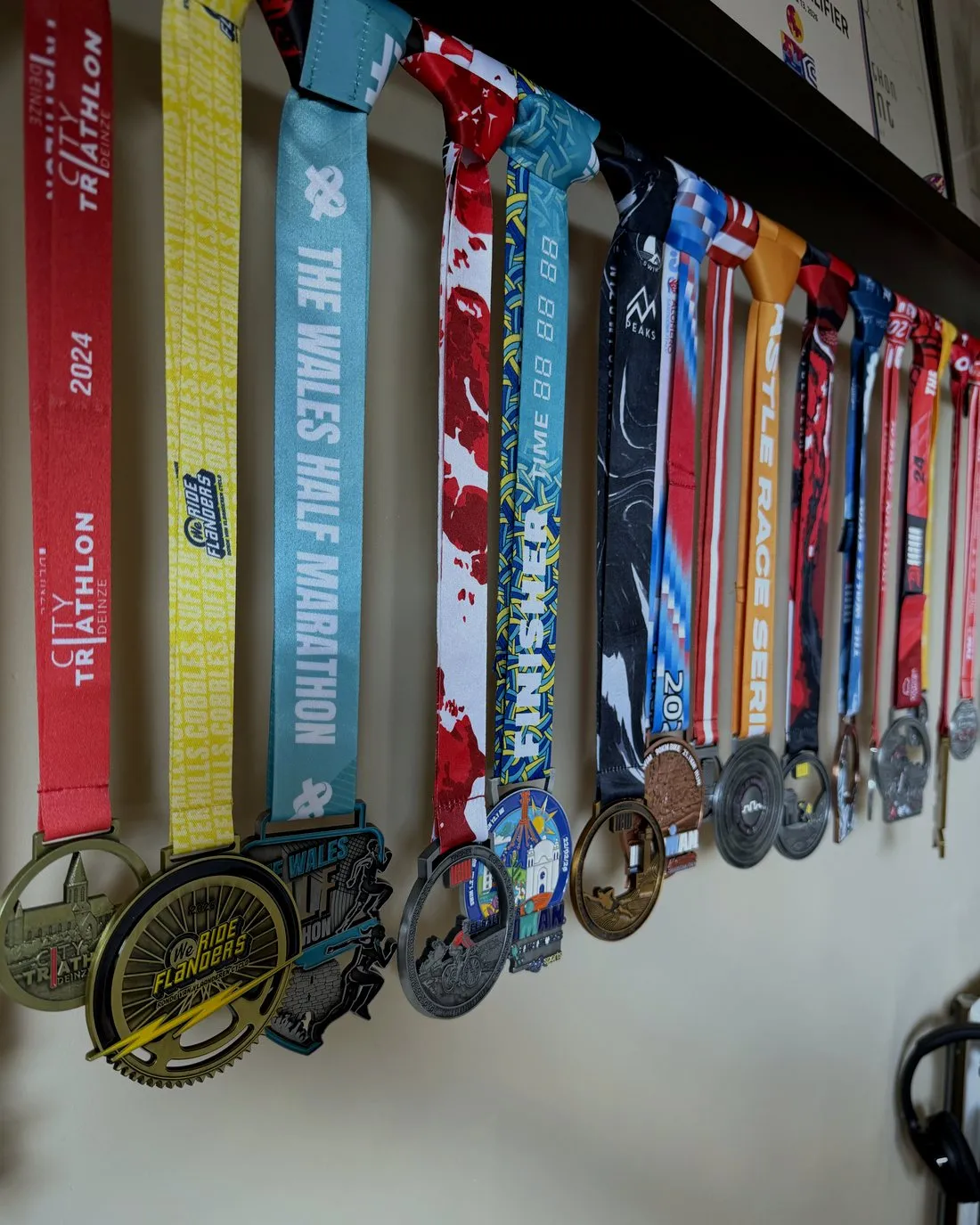Het medaillerek van Jonas met medailles van triatlons, marathons en fietswedstrijden